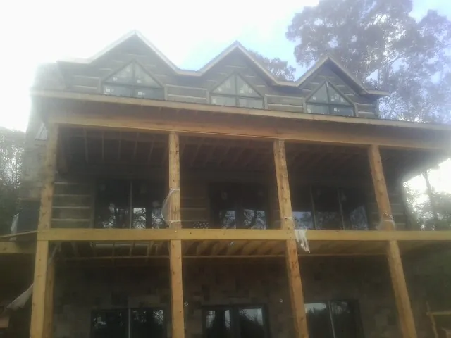 Dormers and porch framing on a large log home under construction — Roof Coating work by our crew in Suitland