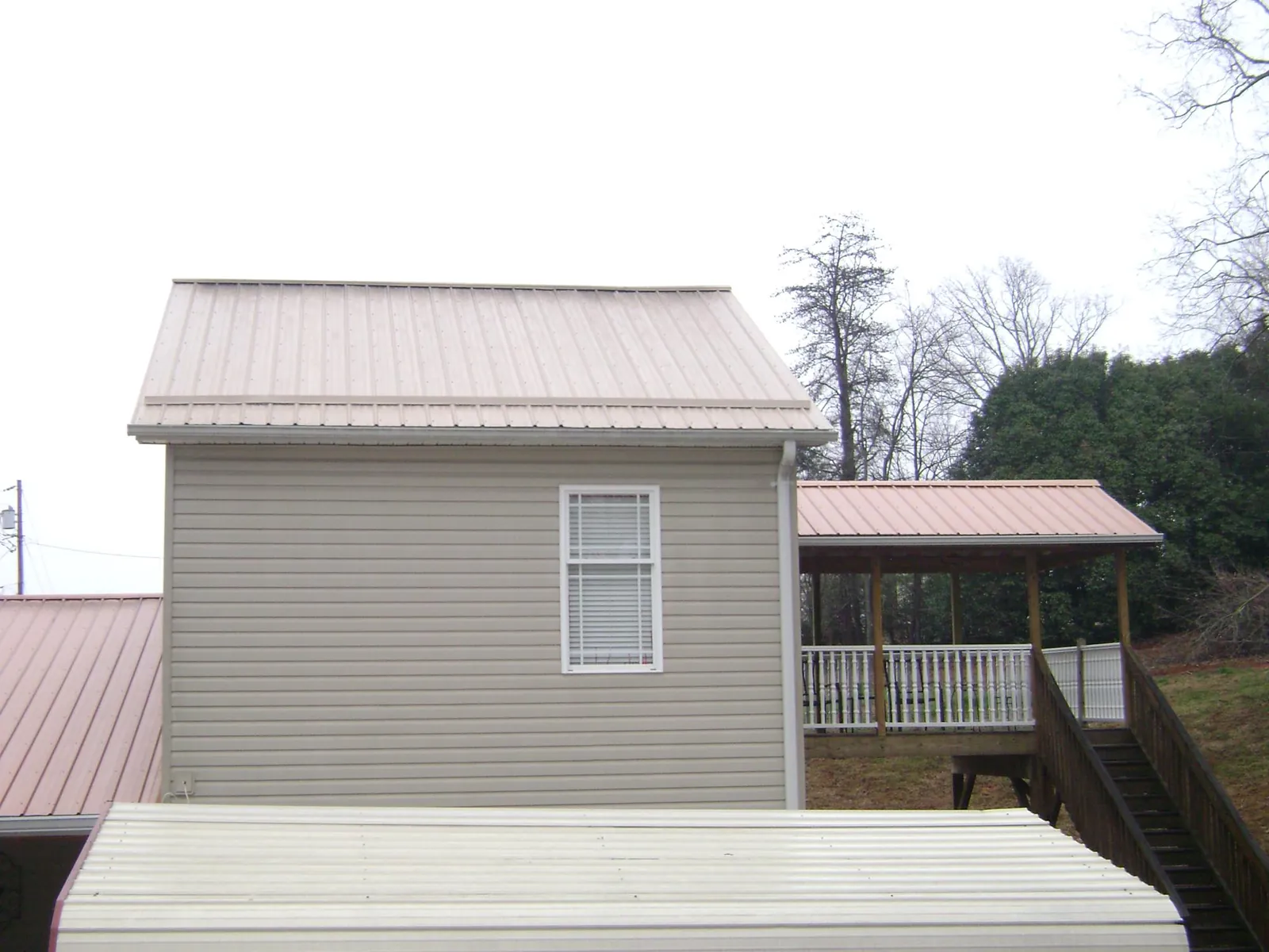 Tan metal roofs on a two story addition and attached porch, from a Roof Replacement job in Suitland