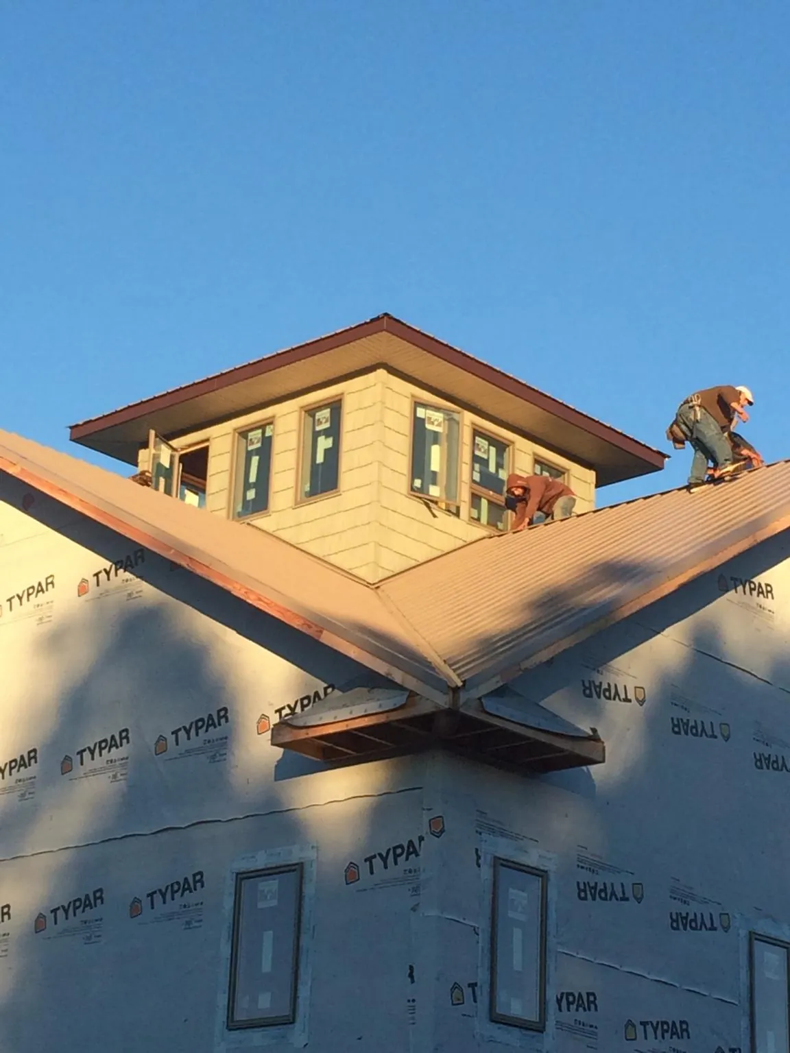 Roofers working around a rooftop cupola on a new metal roof at sunset — Roof Waterproofing in Suitland by Roofing Brothers